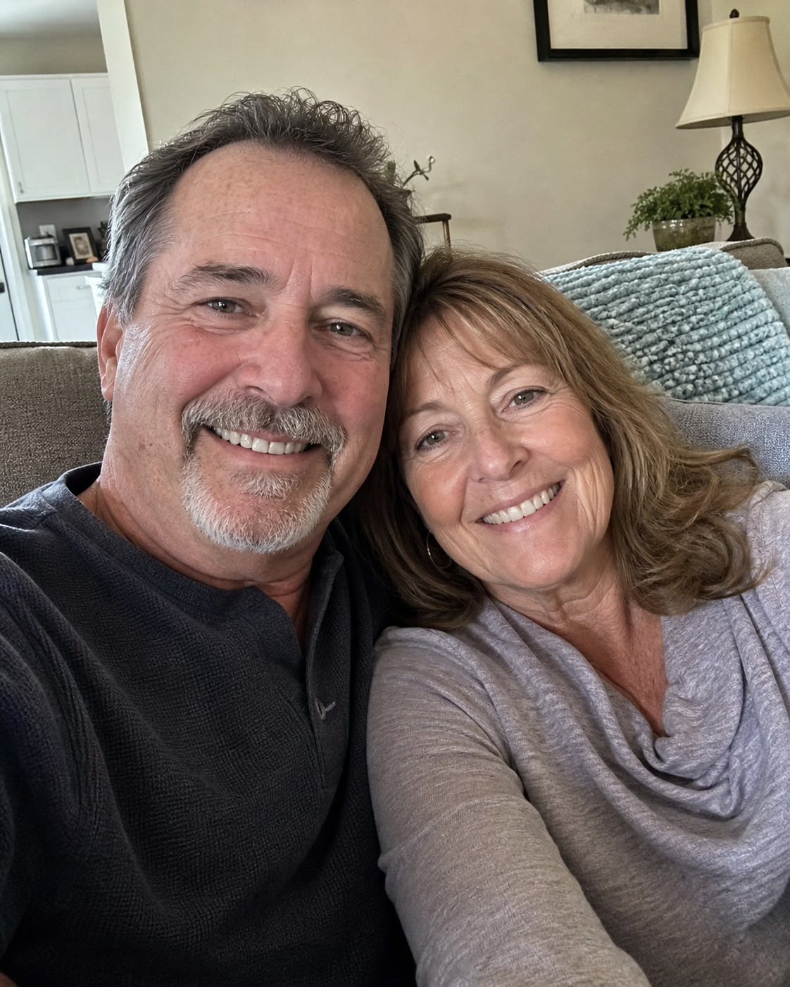 An older couple sitting together on a living room couch